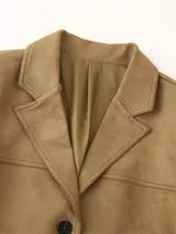 Blazer marrón de gamuza con cuello de solapa, cierre con botones y bolsillos frontales.