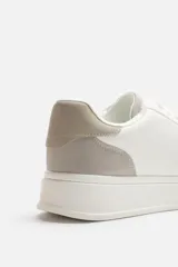 Zapatillas deportivas blancas con detalle en color gris en el talón y suela con plataforma.