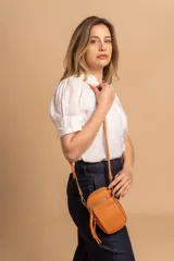 Bandolera compacta de símil cuero color rojo, con correa regulable y desmontable. Posee apertura superior, bolsillo frontal con cierre y bolsillo trasero abierto.