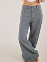 Pantalón gris de tiro medio alto, corte ancho, con bolsillos delanteros y traseros, detalles de atraques y triples costuras en color amarillo.