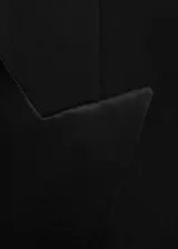 Blazer negro con solapas satinadas, forro interior, cierre frontal con botón, dos bolsillos de ribete y mangas largas abotonadas.