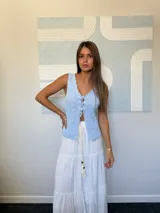 Top tejido de punto color celeste claro, sin mangas, con escote pronunciado en V y cierre frontal mediante lazos anudados. Presenta un patrón texturizado de cuadros.