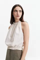 Blusa sin mangas color ladrillo, con cuello halter y elástico en el cuello y la cintura.