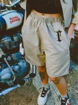 Bermuda color beige de gabardina de algodón con cintura elástica, corte amplio y bordado con logo en una pierna.