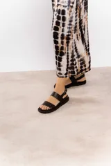 Sandalias negras de cuero con dos tiras anchas en el empeine y hebilla lateral ajustable.