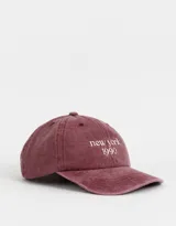 Gorra de denim color borgoña con bordado frontal que dice "New York 1990" en blanco.