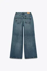 Pantalón de jean azul de tiro alto, corte wide leg, con cinco bolsillos, efecto lavado y cierre frontal con cremallera y botón.