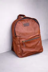 Mochila de cuero color marrón, forrada en lino, con cierres de bronce y un compartimento interior especial para computadora.