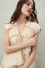 Vestido largo lila con escote con lazo, mangas cortas y frunces en el pecho.