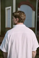 Camisa blanca de popelina con cuello resort, mangas cortas y cierre frontal con botones.