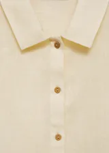 Camisa color crema de lino, con cuello camisero, manga corta con dobladillo y cierre frontal con botones.