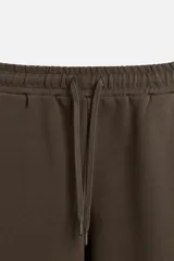 Pantalón negro de corte recto confeccionado en tejido interlock de algodón con elasticidad. Tiene cintura elástica ajustable con cordón, bolsillos frontales y bolsillos traseros de vivo.