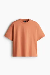 Remera color salmón de corte holgado, cuello redondo y mangas cortas.