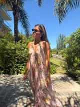 Vestido largo de gasa color rosa con estampado floral, escote halter y corte evasé.