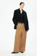 Pantalón ancho color marrón claro con pinzas, bolsillos laterales y trabillas para cinturón.