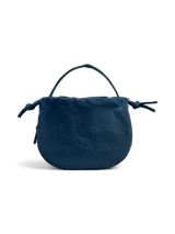 Bolso tipo bombonera confeccionado en denim azul, con asa superior y correa ajustable y desmontable.