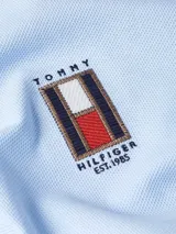 Chomba celeste de piqué de algodón con cuello clásico, tapeta de dos botones y logo vertical bordado en el pecho.