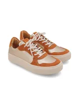 Zapatillas bajas con estampado de vaca en blanco y negro, detalles en gamuza azul y suela marrón.