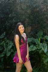 Vestido corto de color verde azulado brillante, con escote halter, espalda descubierta, abertura en la cintura y falda con volados.