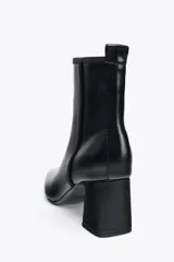 Botín negro de cuero sintético con punta fina y tacón bloque.