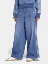 Pantalón de jean Adidas de corte ancho, color azul denim con tres tiras verticales plateadas a los costados y logo bordado en blanco en el bolsillo delantero.