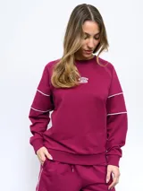 Buzo a la base de felpa color gris claro, sin friza, con cuello redondo y logo Umbro bordado en el pecho. Presenta pipings en contraste color borgoña en hombros y puños.