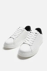 Zapatillas deportivas negras con detalle en blanco en la parte posterior y suela blanca con volumen de diseño irregular.