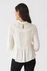 Blusa color crema de viscosa con bordados, mostacillas y encaje. Tiene cuello a la base, mangas largas abullonadas y corte al cuerpo.