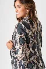 Blazer de poliéster con estampado animal print en tonos grises y beige. Tiene corte ajustado, cuello con solapa y cierre frontal con un botón negro.