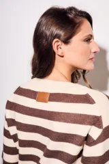 Sweater de punto a rayas horizontales negras y crudas, con cuello redondo y mangas largas. Tiene ribete marrón en puños y ruedo.