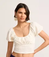 Blusa cropped color blanco, de encaje con escote en U y mangas cortas abullonadas.