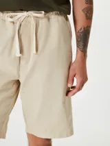 Bermuda color beige de sarga con cintura elastizada y cordón ajustable.