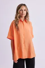 Camisa naranja fluida de manga corta con cuello clásico y cierre con botones.