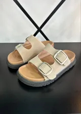 Sandalias de dedo color beige con hebillas plateadas y suela track.