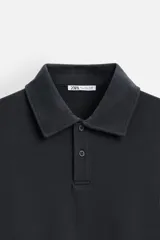 Polo manga larga gris con cuello solapa y cierre frontal de botonadura.