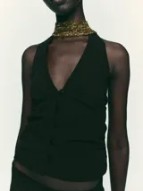 Top negro con cuello halter, escote pico y espalda descubierta. Presenta detalle de frunces laterales y cierre frontal con botones.