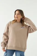 Buzo de felpa en color beige con cuello redondo y estampa de flores en la espalda.