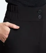 Bermuda blanca de poliéster con cintura elástica, cierre con cremallera y botones, y bolsillos laterales.