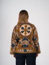 Chaqueta marrón con bordados florales en tonos azul y amarillo.