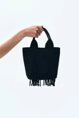 Bolso shopper negro de tejido cepillado con doble asa y flecos largos. Cuenta con cierre magnético oculto en la parte superior, compartimento interior con cierre y forro de tafeta.