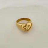 Anillo dorado con forma de corazón y un ángel en el centro, hecho de acero quirúrgico hipoalergénico con baño en oro de 18K.