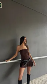 Vestido corto marrón con escote strapless y falda con volados. Incluye cinturón negro con tachas.