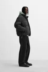 Campera puffer marrón con cuello alto, cierre frontal con cremallera, bolsillos laterales y puños elásticos.