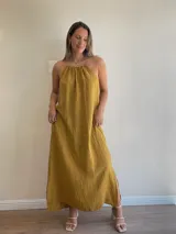 Vestido largo de lino color crudo, con escote halter fruncido y abertura lateral en la falda.