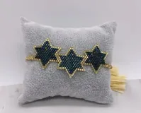 Pulsera tejida con cuentas doradas y azul oscuro, con tres dijes en forma de estrella.