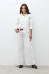 Camisa de jean color crudo, estilo western, con cuello y dos bolsillos frontales con tapa y botón. Presenta costuras contrastantes en tono rojizo.