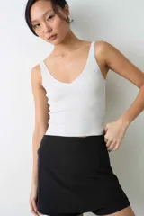 Top de punto rib color blanco, con finos breteles y detalles de lurex que aportan un toque brillante.