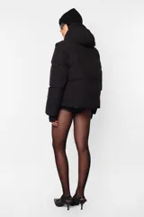 Campera puffer color beige, de corte oversize, con capucha y cuello alto. Tiene cierre frontal con abrojo y cierre metálico, bolsillos laterales con cierre, mangas desmontables con mitones y cintura ajustable con elástico y tancas.