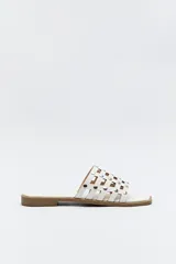 Sandalia baja negra con diseño entrelazado y apliques metálicos.