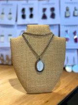 Collar plateado con cadena de eslabones y dije ovalado con piedra blanca.